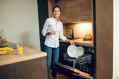 Mutfakta. Mutfakta bulaşıkçının yanındaki siyah saçlı genç kadın.