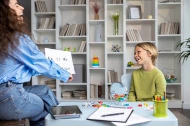 Konuşma dersi için. Sarışın çocuk, kadın bir konuşma terapistiyle konuşma dersi veriyor.