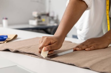 Moda atölyesindeki kadın tebeşirle modern tekstil ve yaratıcı fikirleri olan şık bir elbise tasarlıyor.