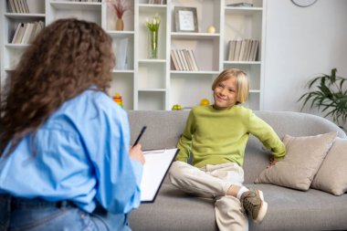 Sohbet. Uzun saçlı bir kadın sarışın bir çocukla konuşuyor ve ikisi de işin içinde gibi görünüyor.