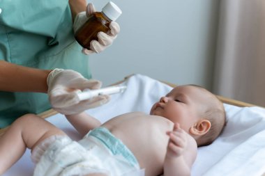 Tanınmayan doktor, klinikteki hasta bebeğe bir doz şurup veriyor.