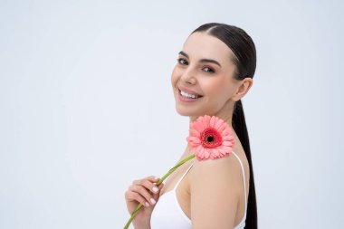 Uyum. Elinde çiçekle güzel, narin, genç bir kadın. Rahatlamış görünüyor.