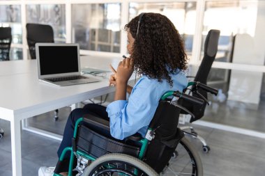 Özürlü Afrikalı bir kadın çağrı merkezinde çalışıyor. Laptop ve kulaklıkla müşterilere destek ve umut veriyor.