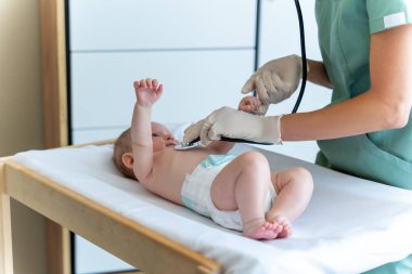 Tıbbi klinikte bebeğe sağlık kontrolü yapan kimliği belirsiz bir kadın çocuk doktoru.