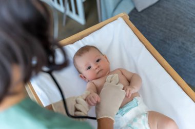 Tıbbi klinikte bebeğe sağlık kontrolü yapan kimliği belirsiz bir kadın çocuk doktoru.