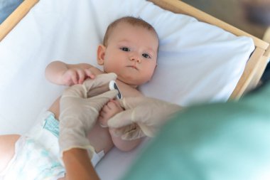 Hastanedeki bebek vücut ısısını ölçen dijital termometre tutan isimsiz bir doktor.