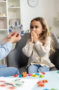 Konuşma terapisi seansı. Güzel küçük kız konuşma terapistiyle antrenman yapıyor.