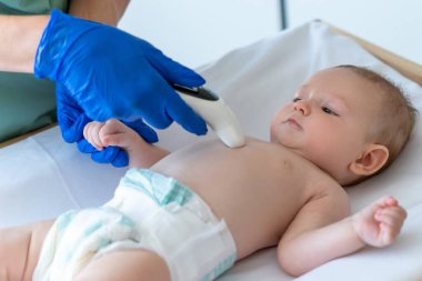 Tanımlanamayan doktorlar termometreyi çocuğun vücuduna tutarak vücut ısısını ölçüyorlar.