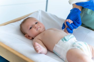 Mavi eldivenli doktor ya da hemşire bebek sıcaklığını dijital termometreyle izliyor.