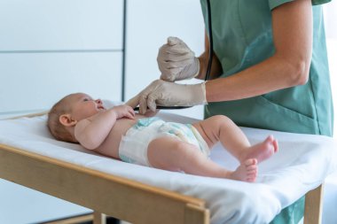 Tanımlanamayan tıp doktoru, klinikteki randevusu sırasında yeni doğan bebeği muayene eder.