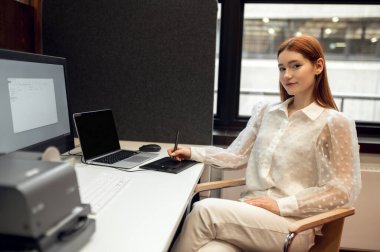 Yoğun bir gün. Ginger güzel genç bayan masada oturuyor ve meşgul görünüyor.