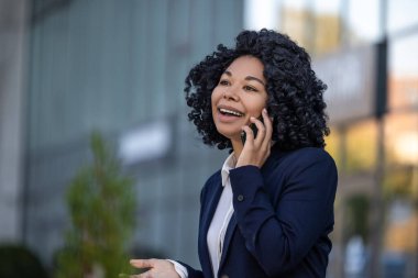 Telefon var. Kıvırcık saçlı, güzel, olgun bir kadın telefonda konuşuyor ve mutlu görünüyor.