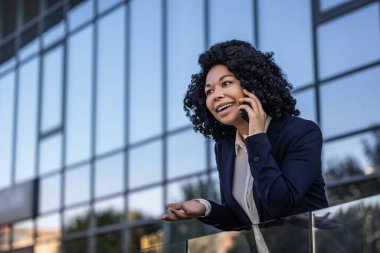 Telefon var. Kıvırcık saçlı, güzel, olgun bir kadın telefonda konuşuyor ve mutlu görünüyor.