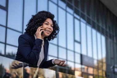 Telefon var. Kıvırcık saçlı, güzel, olgun bir kadın telefonda konuşuyor ve mutlu görünüyor.