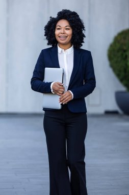 İş kadını. Elinde dizüstü bilgisayarla duran takım elbiseli güzel bir kadın.