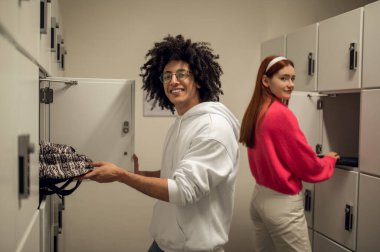 Dolapların yanında. Dolapların yanında duran ve konuşan iki genç insan.