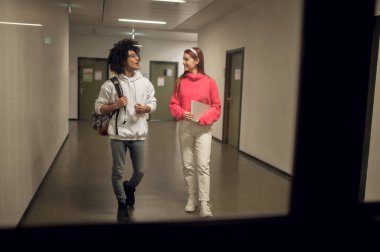 Sohbet. Koridorda konuşan ve araştıran iki genç var.