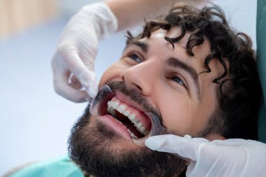 Tedavi sırasında dişçi muayenehanesinde dişçi aletleriyle sakallı hasta.