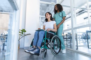 Doktor ve hasta. Klinik koridorunda tekerlekli sandalyeli bir hastası olan Afrikalı Amerikalı bir kadın doktor.