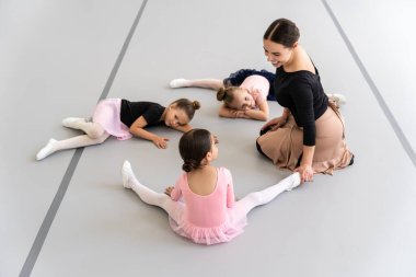 Stüdyoda birlikte esneme çalışması yapan bir grup öğrenciye bale öğreten kadın.