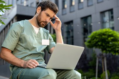 Hastane yakınlarında internette sörf yapan, üniformalı, düşünceli bir doktor.