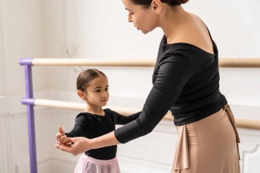 Bale öğretmeni, küçük kızı açık modern stüdyoda bale barında eğitiyor.