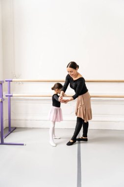 Bale sınıfında genç kızı eğiten zarif bir kadın stüdyoda klasik dans figürlerini öğretiyor.
