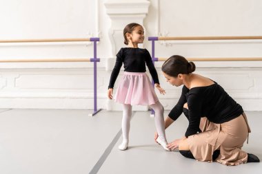 Klasik bale dersinde genç bir kızı çalıştıran zarif hareketlerine yardımcı olan zarif bir bayan antrenör.