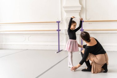 Klasik bale dersinde genç bir kızı çalıştıran zarif hareketlerine yardımcı olan zarif bir bayan antrenör.