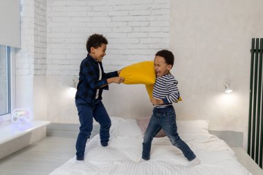 Yastık savaşı. İki kardeş yastık savaşı yapıyor ve heyecanlı görünüyorlar.