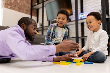 Jenga oynuyorum. Koyu tenli bir adam çocuklarıyla Jenga oynuyor ve olaya dahil olmak istiyor.