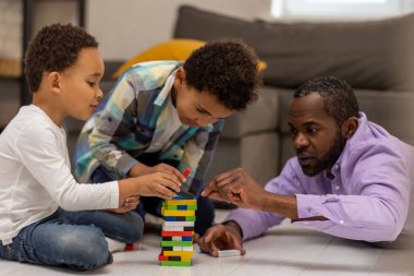 Jenga oynuyorum. Koyu tenli bir adam çocuklarıyla Jenga oynuyor ve olaya dahil olmak istiyor.