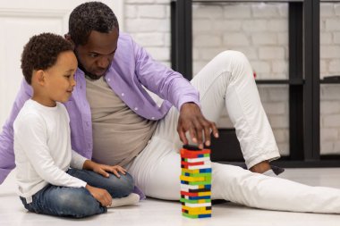 Maç zamanı. Afrika kökenli Amerikalı bir aile yerde oturup Jenga oynuyor.