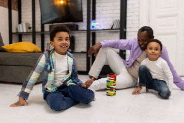 Maç zamanı. Afrika kökenli Amerikalı bir aile yerde oturup Jenga oynuyor.