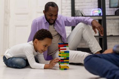 Maç zamanı. Afrika kökenli Amerikalı bir aile yerde oturup Jenga oynuyor.