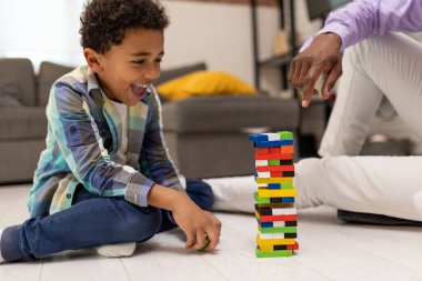 Boş zaman. Koyu tenli çocuk ailesiyle Jenga oynarken olaya dahil olmuş ve odaklanmış görünüyor.
