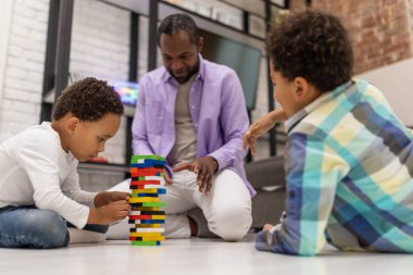 Birlikte oynuyoruz. Afrikalı Amerikalı sakallı bir adam oğullarıyla oynarken olaya dahil olmuş gibi görünüyor.