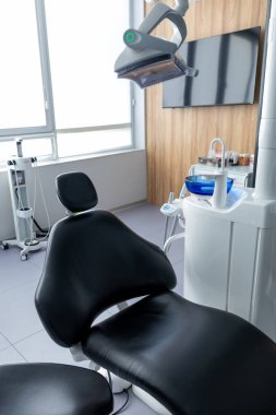 Yeni modern klinik odasındaki boş dişçi muayenehanesinde diş aletleri, diş hekimleri için dişçi koltuğu ve aksesuarları