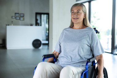 Rehabilitasyon. Rehabilitasyon merkezinde tekerlekli sandalyede oturan gri tişörtlü bir kadın.