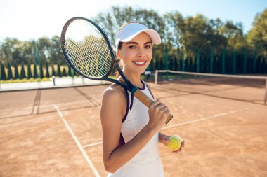 Kendine güvenen bir tenis oyuncusu. Kendine güvenen kadın tenisçi elinde raketle heyecanlı görünüyor.