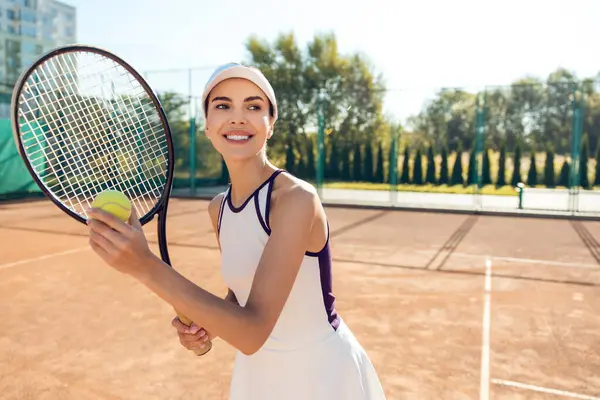 Kendine güvenen bir tenis oyuncusu. Kendine güvenen kadın tenisçi elinde raketle heyecanlı görünüyor.