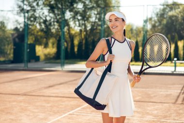 Kendine güvenen bir tenis oyuncusu. Beyaz şapkalı güzel gülümseyen tenisçi kendinden emin görünüyor.