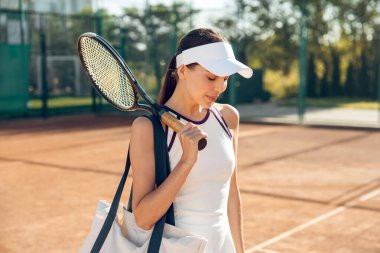 Kendine güvenen bir tenis oyuncusu. Beyaz şapkalı güzel gülümseyen tenisçi kendinden emin görünüyor.