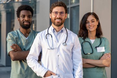 Doktorlar iş başında. Bir grup doktor klinik binasının yanında dikilirken kendinden emin ve kararlı görünüyorlar.