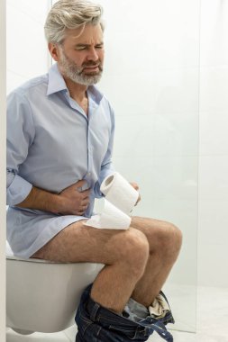 Indigestion. Man sitting in a toilet and having problems with digestion clipart