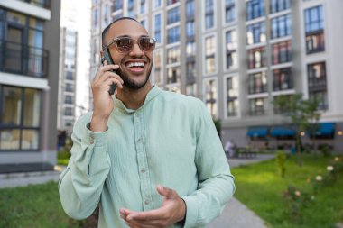 Yakışıklı Afro-Amerikan bir adam cep telefonuyla şehir dışından arıyor.