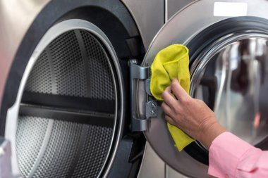 Temizlik. Çamaşır makinesinin varilini temizleyen bir kadının resmini kapat.