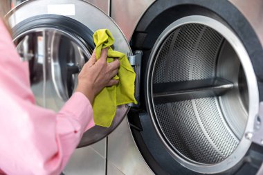 Temizlik. Çamaşır makinesinin varilini temizleyen bir kadının resmini kapat.