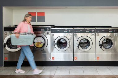 Çamaşırhanedeki kadın. Çamaşırhanede elinde giysileri olan olgun bir kadın.