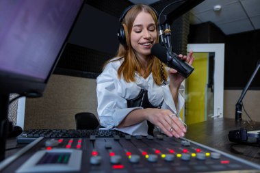 Sarışın kadın radyo sunucusu radyo istasyonunda canlı yayın yapıyor.